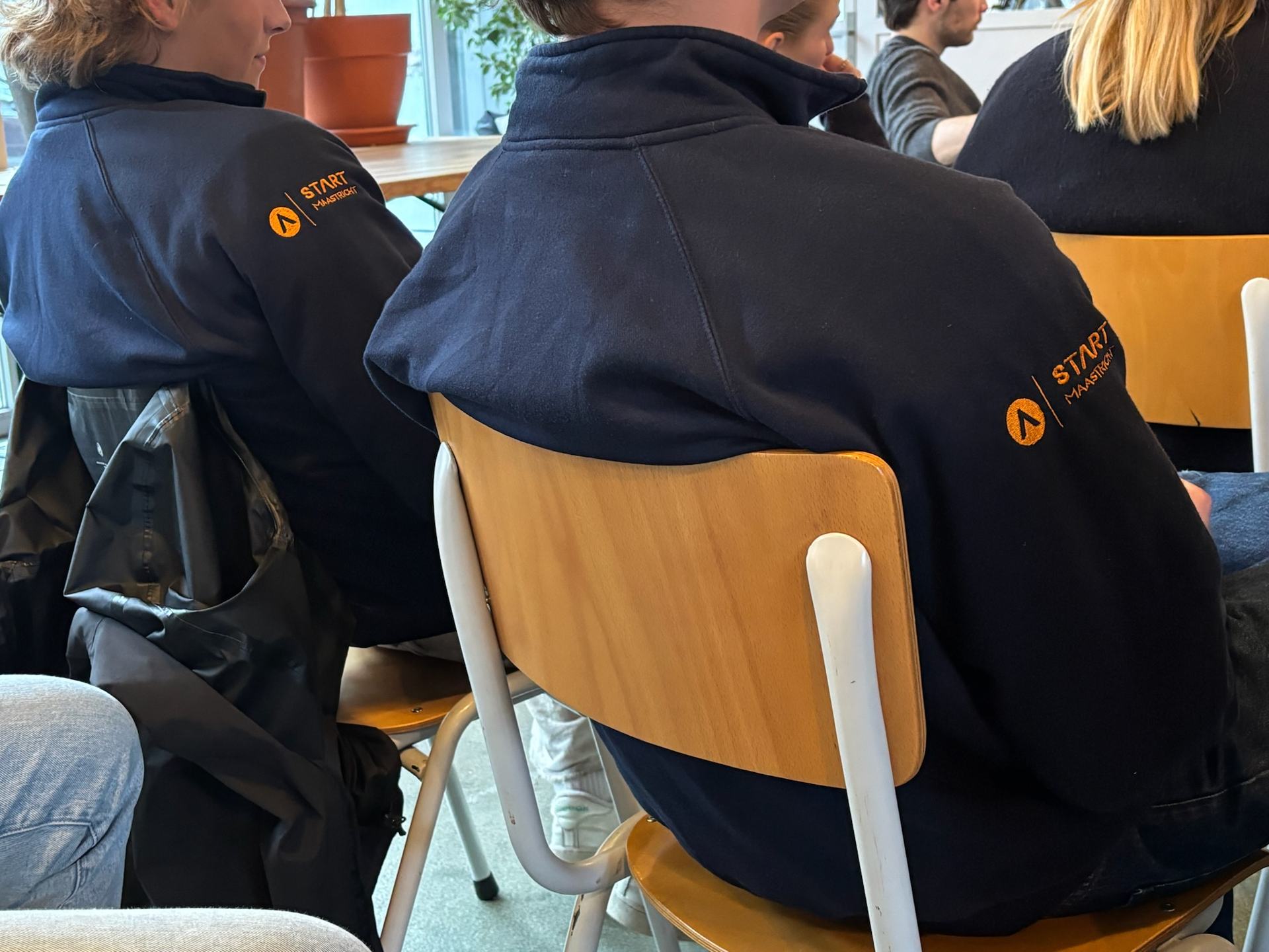 Two START Maastricht members wearing START sweatshirts at an event